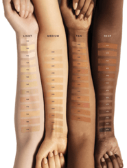 four forearms of different skin tone with gradient shades of sunscreen
